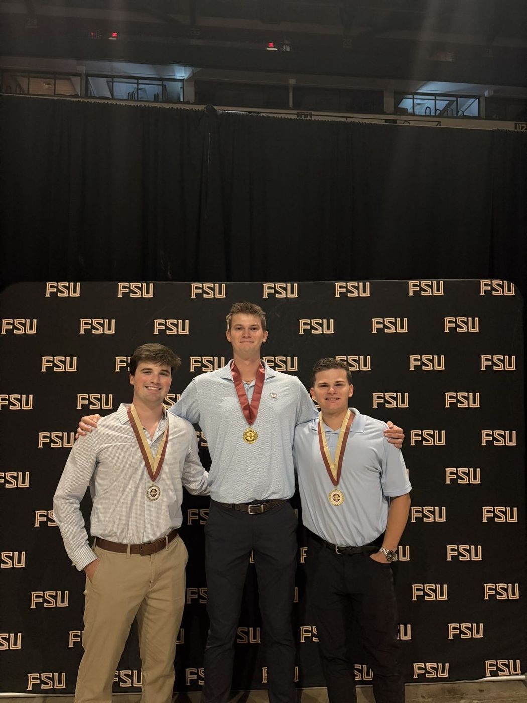 Cole wearing an honors medal with two classmates in front of a Florida State backdrop